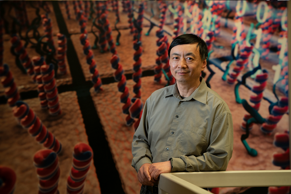 Dr. Wenzhong Xiao standing in front of a colorful, science-themed background.