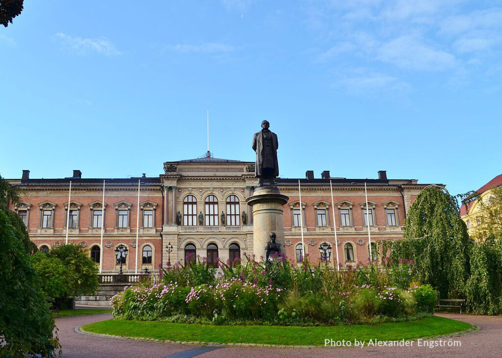 L'image représente un grand bâtiment de l'Université d'Uppsala, mettant en avant un design architectural classique. L'édifice présente une façade symétrique avec des fenêtres en arc au rez-de-chaussée et des fenêtres rectangulaires aux étages supérieurs, toutes encadrées de moulures décoratives.