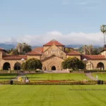 Une vue du campus emblématique de l'Université Stanford avec ses bâtiments distinctifs aux toits rouges et ses jardins bien entretenus.