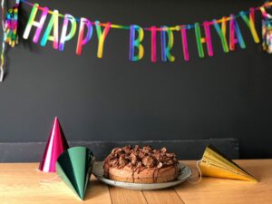 A cake, party hats, and a streamer that reads "Happy birthday."