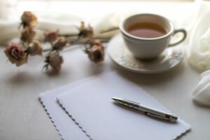 A desktop with blank paper, a pen, and a cup of coffee