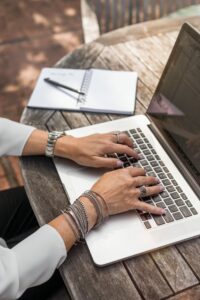 Les mains sur un clavier. Un cahier ouvert à proximité