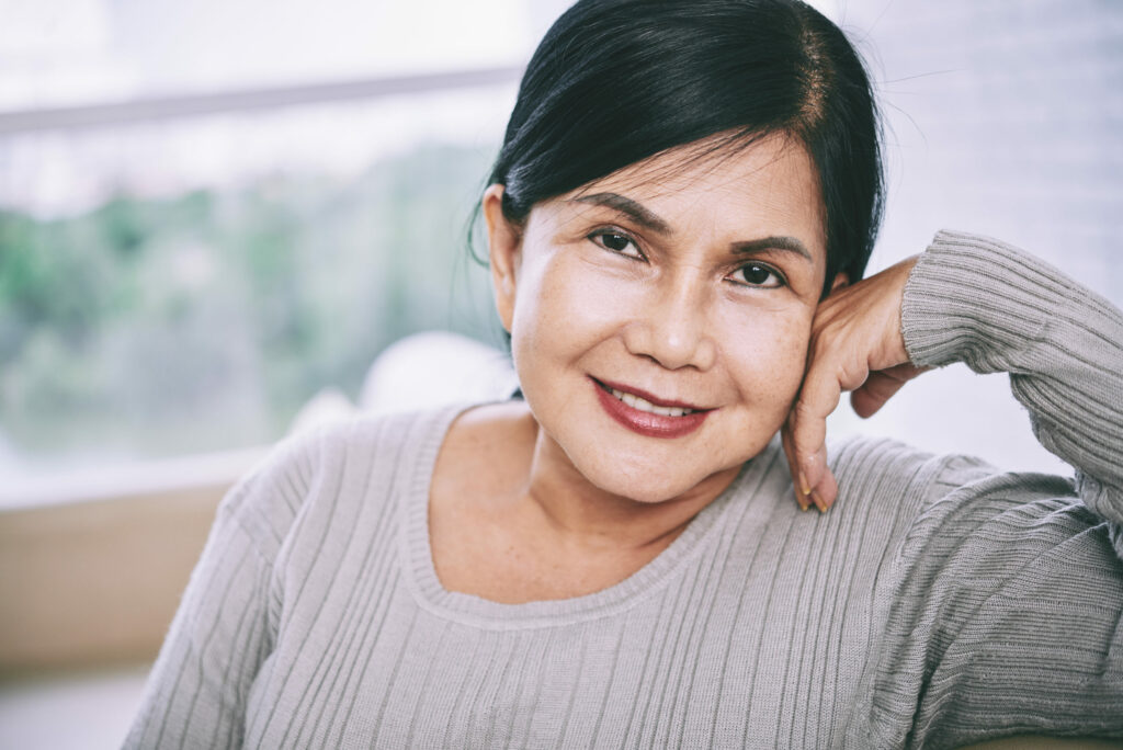 Mature woman leaning on her left arm and smiling