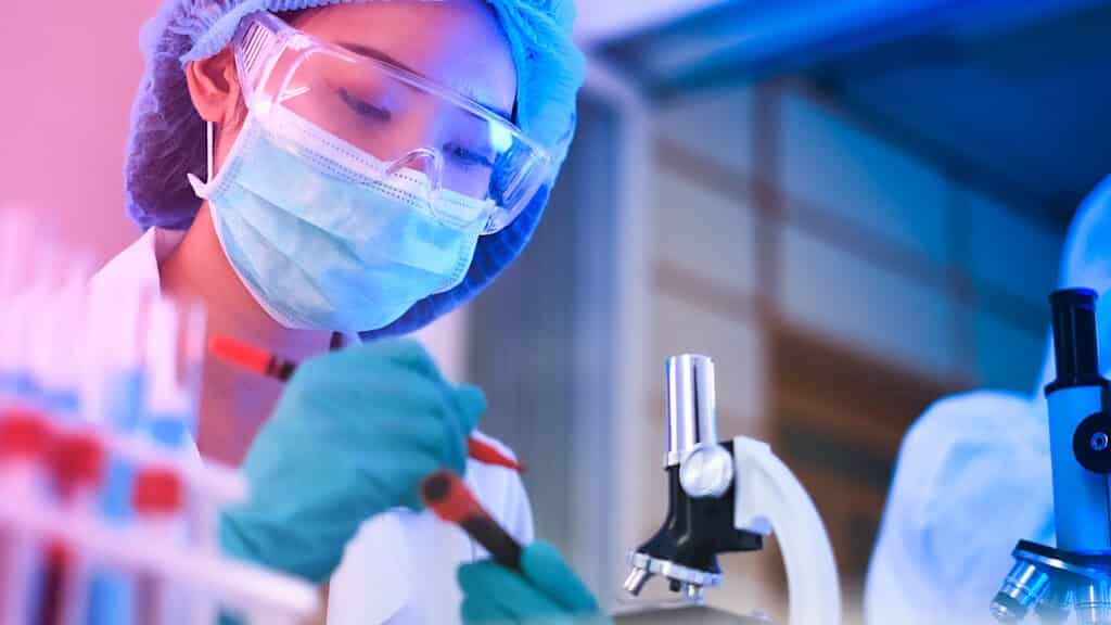 Woman researcher in a lab, microscope in the background