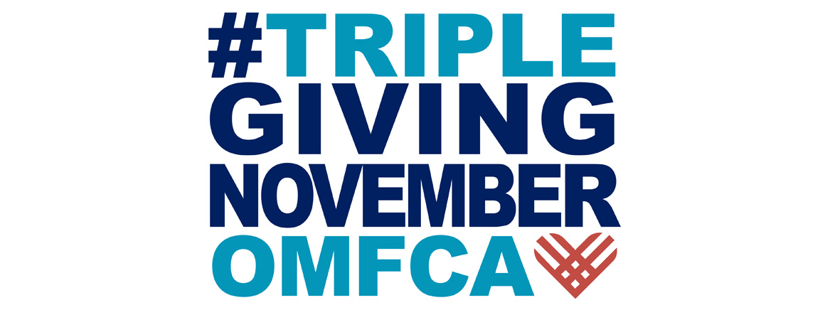 TGN logo:  #TRIPLEGIVINGNOVEMBEROMF. The phrase is written in bold, uppercase letters with a mix of dark blue and light blue colors. The "OMF" text is in light blue, and there is a stylized heart shape in reddish-orange next to it.