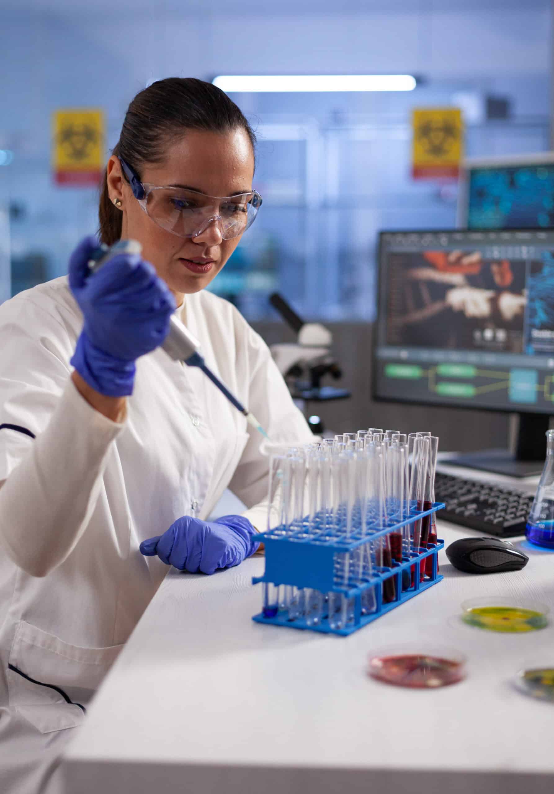 Woman chemist dropping liquid in tubes