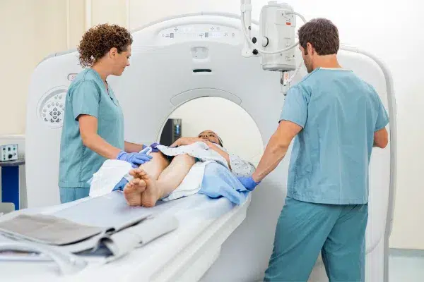 we see a PET (Positron Emission Tomography) scan in progress within a medical facility. The patient is lying on a narrow bed that is part of the PET scanning machine.