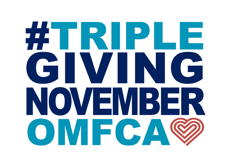 TGN logo: #TRIPLEGIVINGNOVEMBEROMFCA. The phrase is written in bold, uppercase letters with a mix of dark blue and light blue colors. The "OMFCA" text is in light blue, and there is a stylized heart shape in reddish-orange next to it.