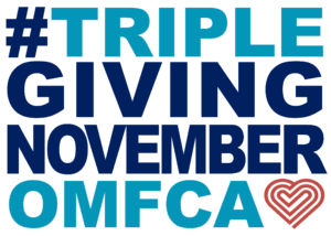 TGN logo:  #TRIPLEGIVINGNOVEMBEROMF. The phrase is written in bold, uppercase letters with a mix of dark blue and light blue colors. The "OMF" text is in light blue, and there is a stylized heart shape in reddish-orange next to it.