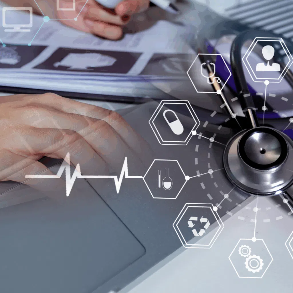 Hands using a laptop next to a stethoscope, overlaid with medical icons and an ECG line, illustrating medical research.