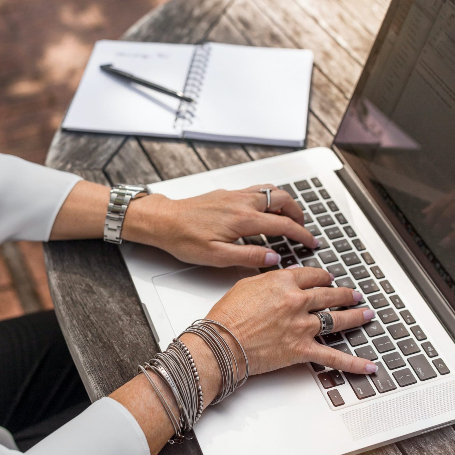 Hands on a keyboard. An open notebook nearby